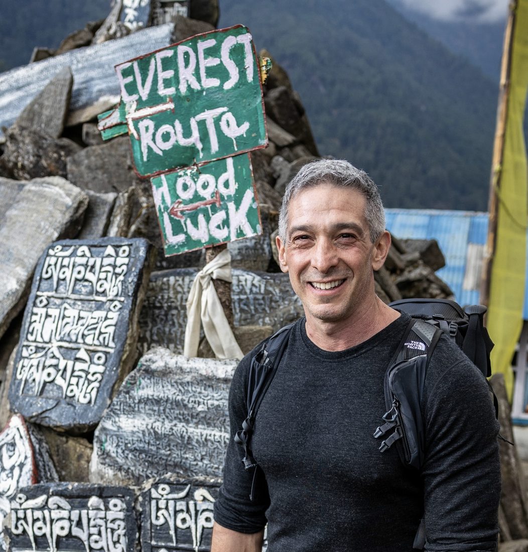 Andre Dupuis smiling beside the Everest Route sign in Nepal